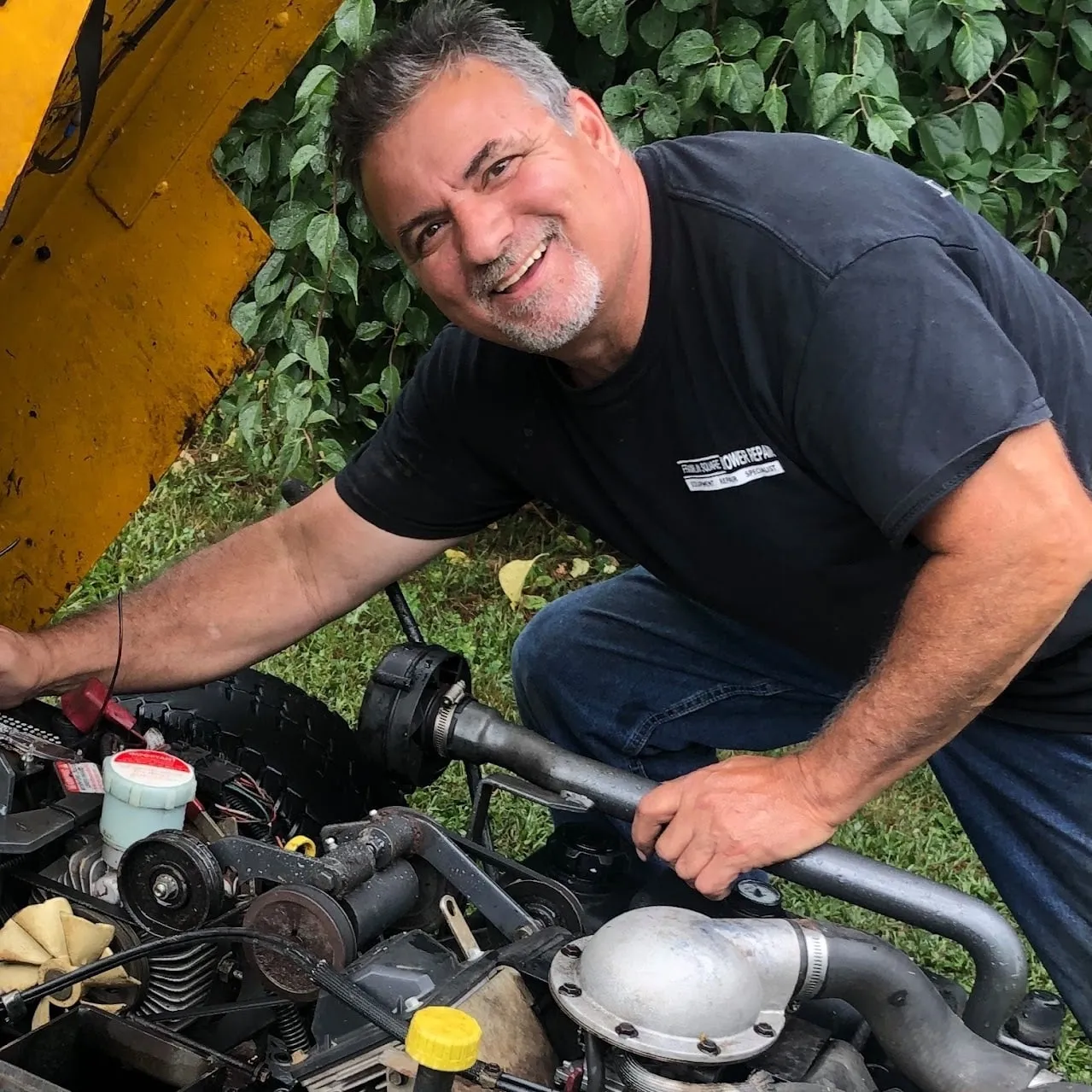 Pete, the owner of Franklin Square Mower Repair, working on a riding mower engine