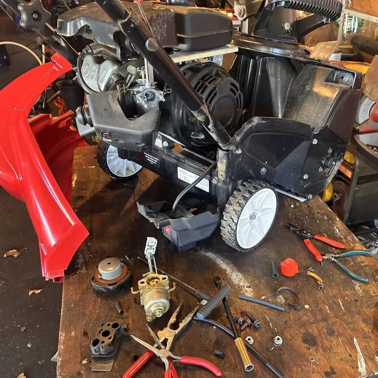 Snowblower on the bench with its carburetor and fuel parts removed